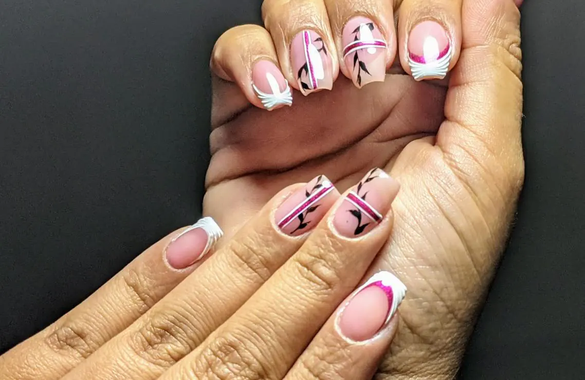 Manos con uñas en tono nude, diseño de líneas fucsia y francesa blanca